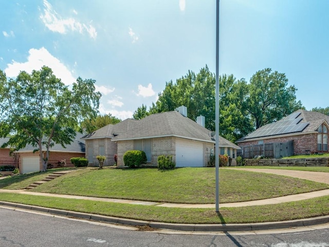 ranch-style house featuring driveway, brick siding, an attached garage, and a front lawn