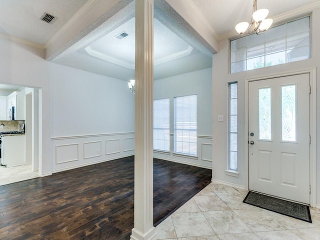 entryway with an inviting chandelier, visible vents, and decorative columns