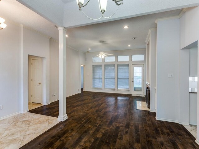 unfurnished living room with hardwood / wood-style floors, recessed lighting, ornamental molding, decorative columns, and ceiling fan with notable chandelier