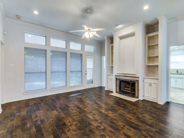 unfurnished living room featuring dark wood-style floors, a ceiling fan, a tiled fireplace, and crown molding