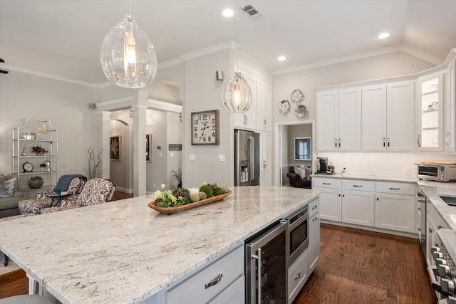 kitchen with light stone countertops, wine cooler, white cabinetry, ornate columns, and appliances with stainless steel finishes