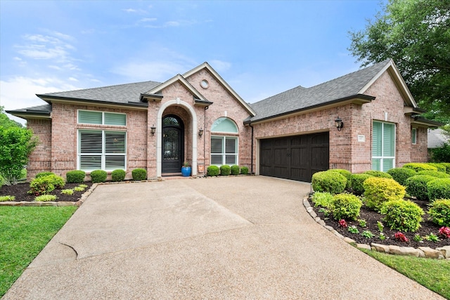 view of front facade featuring a garage, brick siding, a shingled roof, and concrete driveway