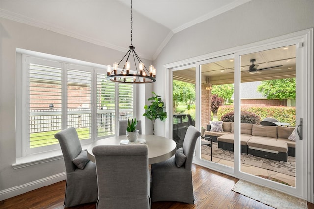 dining area with lofted ceiling, ornamental molding, dark wood-style floors, and ceiling fan with notable chandelier