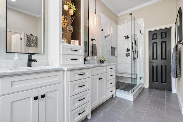 full bathroom featuring a stall shower, double vanity, crown molding, and a sink