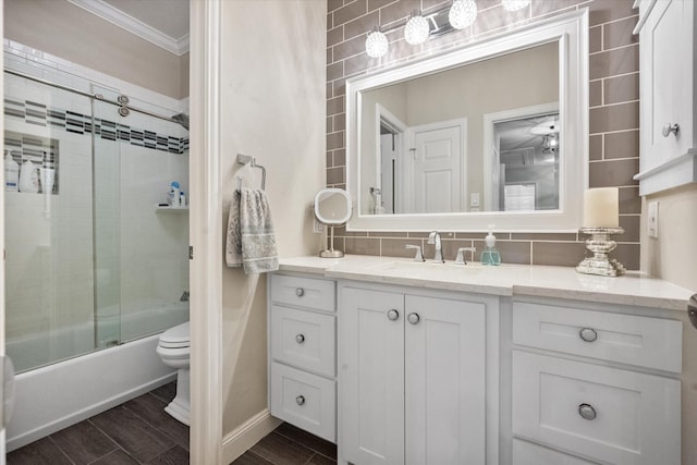 full bath with tasteful backsplash, shower / bath combination with glass door, toilet, ornamental molding, and vanity