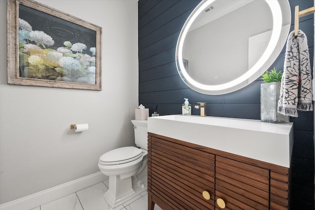 half bathroom with marble finish floor, toilet, vanity, baseboards, and wooden walls