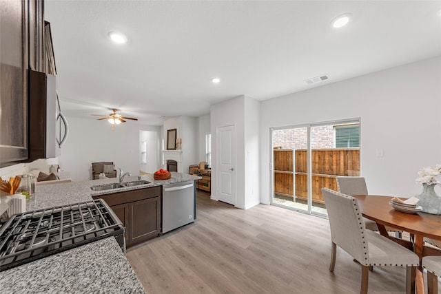 kitchen with visible vents, appliances with stainless steel finishes, dark brown cabinets, a sink, and light wood-style flooring