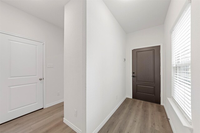 hall with light wood-style floors and baseboards
