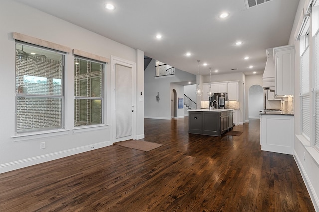 3404 Ophel Way, Flower Mound, TX 75028 - kitchen with arched walkways, white cabinets, a kitchen island with sink, and dark wood-style floors