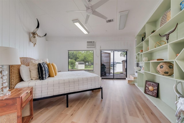 bedroom featuring visible vents, access to exterior, light wood-style floors, a wall mounted air conditioner, and a ceiling fan