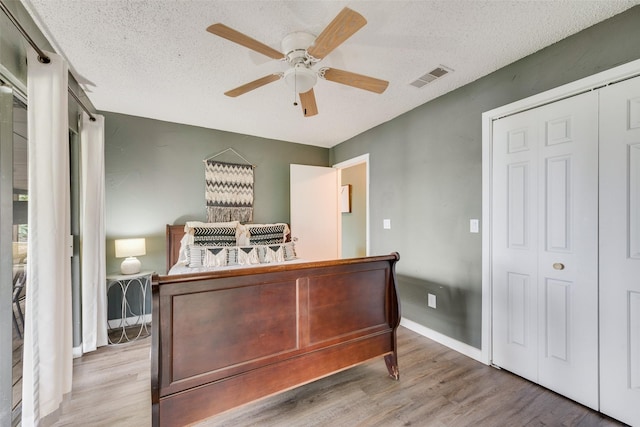 bedroom featuring ceiling fan, a textured ceiling, visible vents, and wood finished floors