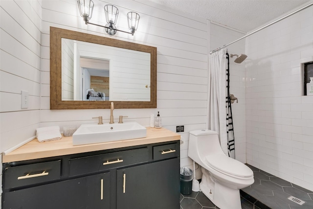 full bath featuring wooden walls, a tile shower, vanity, toilet, and a textured ceiling