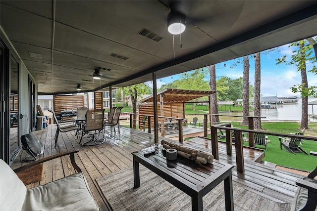 deck with visible vents, ceiling fan, a water view, outdoor dining area, and a yard