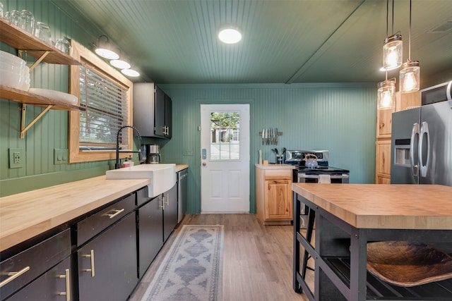 kitchen with a sink, stainless steel fridge, butcher block counters, and light wood-style floors