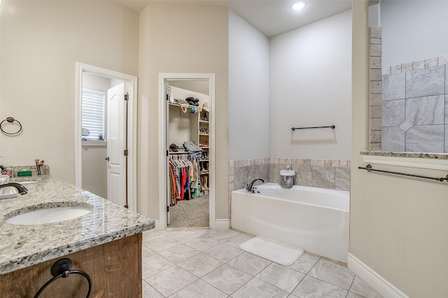 full bath with baseboards, tile patterned floors, a garden tub, vanity, and a walk in closet