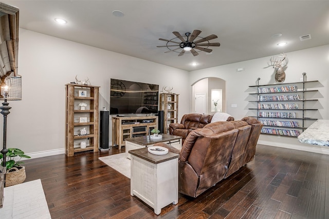 living room with baseboards, arched walkways, dark wood-style floors, visible vents, and a ceiling fan
