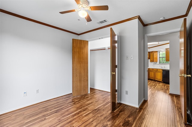 unfurnished bedroom featuring crown molding, visible vents, a closet, wood finished floors, and a ceiling fan