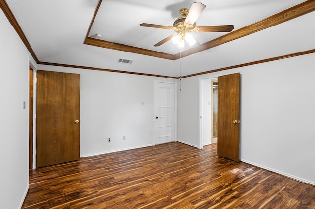 unfurnished room with wood finished floors, ornamental molding, ceiling fan, visible vents, and a tray ceiling