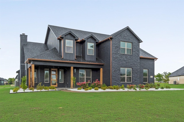 craftsman-style house featuring stone siding, a front yard, a chimney, board and batten siding, and a porch