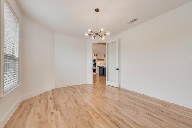 unfurnished dining area with light wood-style floors, baseboards, a notable chandelier, and visible vents