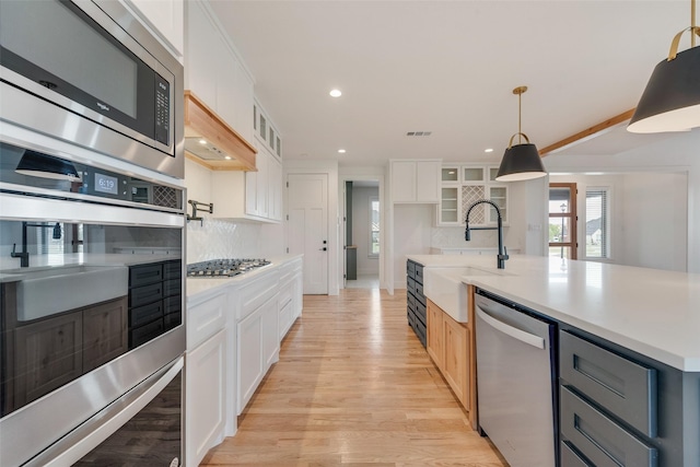kitchen featuring light countertops, a sink, light wood-style floors, and stainless steel appliances