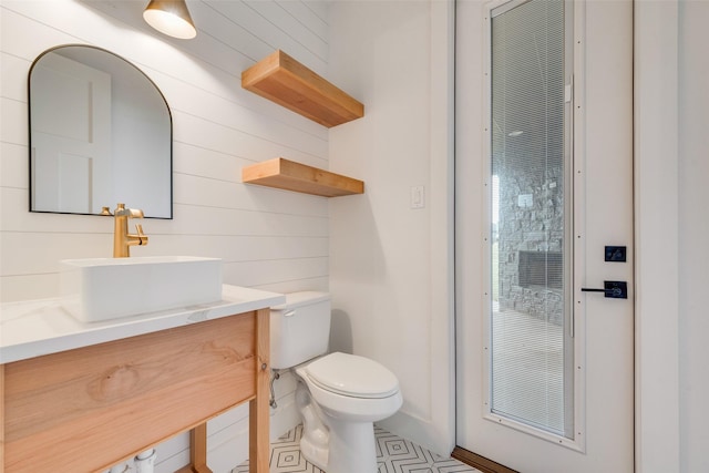 bathroom with vanity, tile patterned flooring, toilet, and wood walls