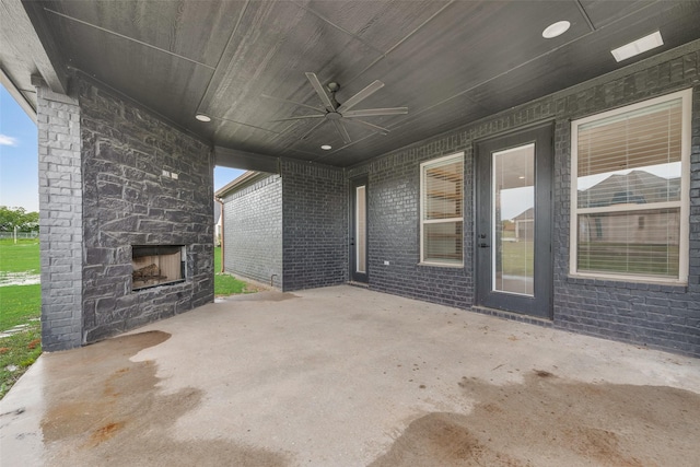 view of patio with an outdoor stone fireplace and a ceiling fan