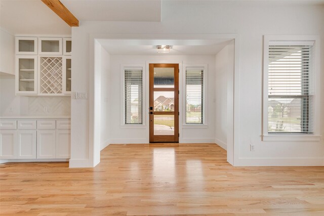 entryway with baseboards, beamed ceiling, and light wood-style flooring