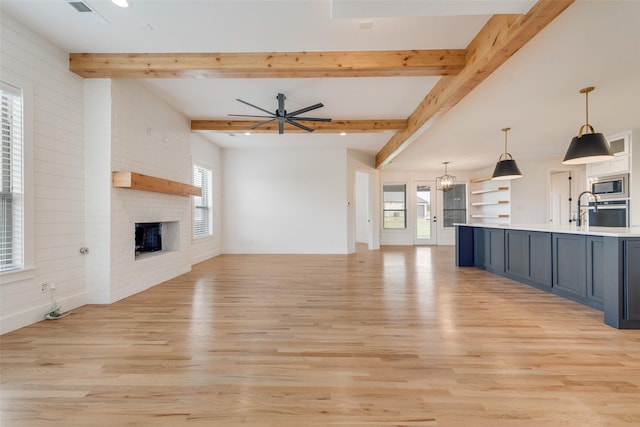 1001 Devoss Ct, Caddo Mills, TX 75135 - unfurnished living room featuring a ceiling fan, beam ceiling, a fireplace, baseboards, and light wood-style floors