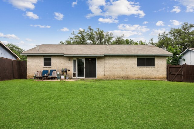 rear view of house with fence, a shingled roof, a yard, and brick siding