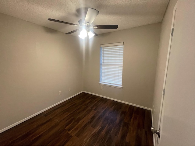 empty room with a textured ceiling, a ceiling fan, dark wood finished floors, and baseboards