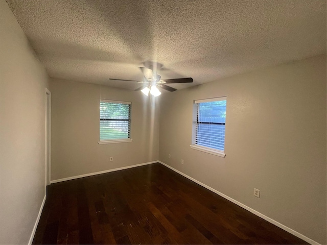 spare room with dark wood-type flooring, ceiling fan, baseboards, and a textured ceiling