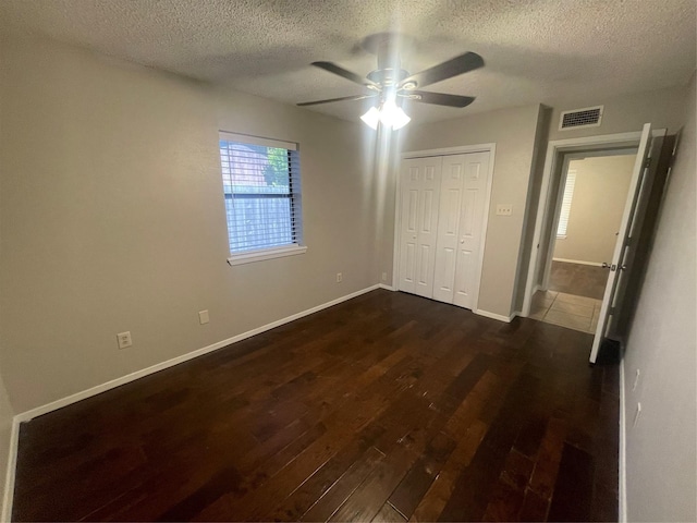 unfurnished bedroom featuring a textured ceiling, visible vents, and dark wood-type flooring