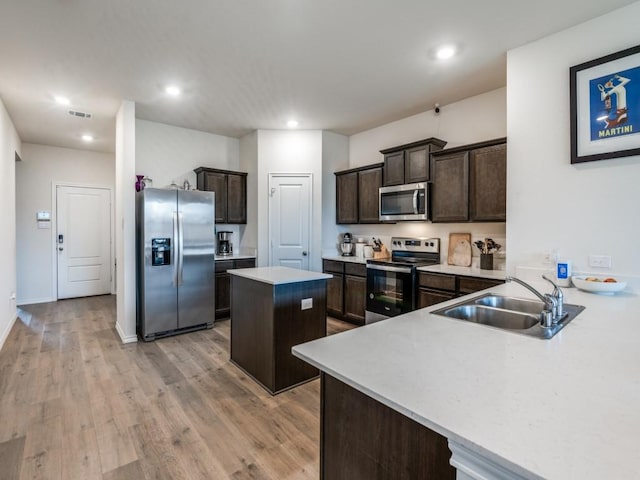 kitchen featuring a sink, appliances with stainless steel finishes, a kitchen island, light countertops, and dark brown cabinets