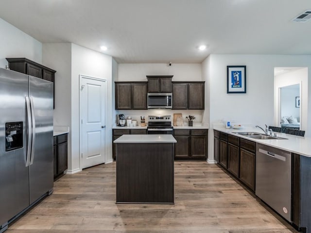 kitchen featuring a sink, appliances with stainless steel finishes, visible vents, dark brown cabinetry, and light wood finished floors