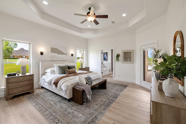 bedroom featuring light wood finished floors, access to outside, a raised ceiling, visible vents, and baseboards