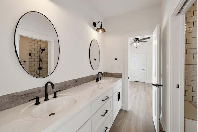 full bathroom featuring wood finished floors, a ceiling fan, double vanity, and a sink