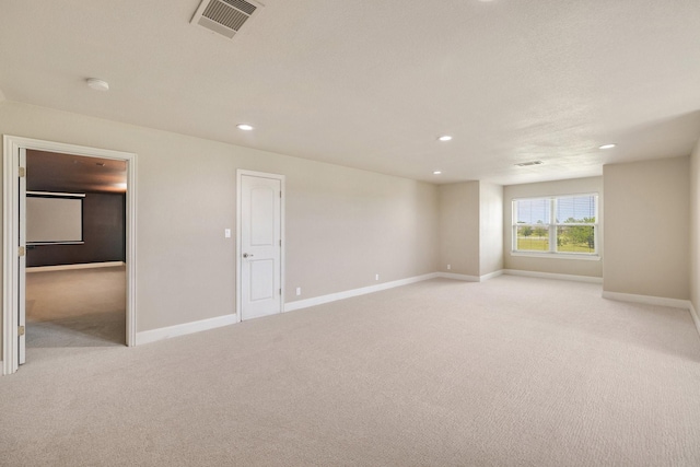 spare room featuring light colored carpet, visible vents, recessed lighting, and baseboards