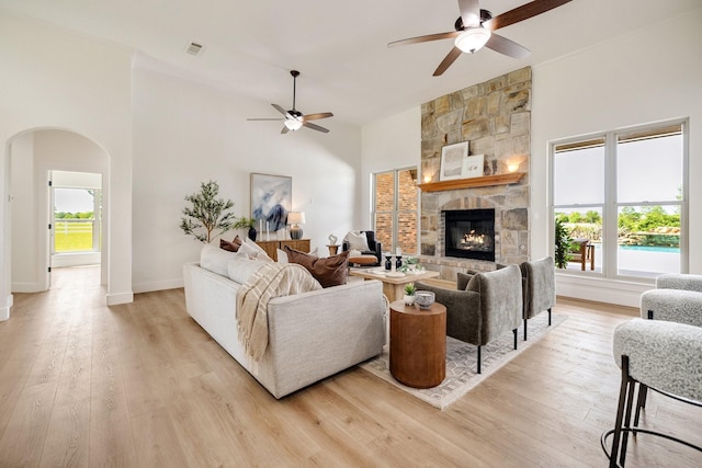 living area featuring arched walkways, ceiling fan, a wealth of natural light, and light wood-type flooring