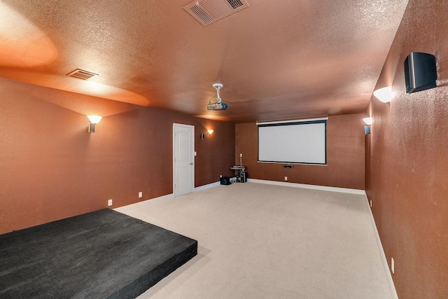 carpeted cinema room with a textured ceiling, visible vents, and baseboards