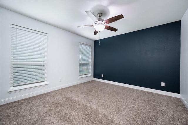 carpeted spare room featuring ceiling fan and baseboards