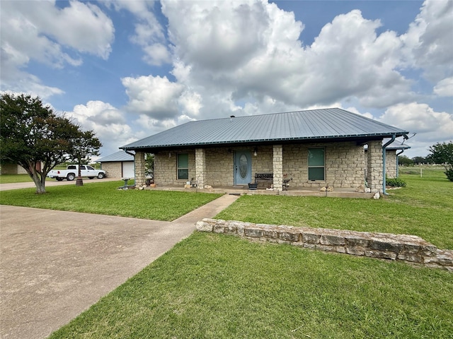 view of front of property with a front yard, metal roof, and stone siding