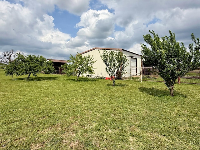 view of yard featuring a pole building, a garage, an outbuilding, and fence