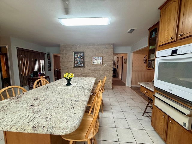 kitchen featuring a warming drawer, oven, brown cabinets, a center island, and a kitchen breakfast bar