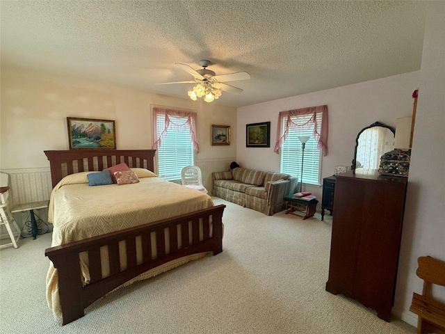 bedroom with a ceiling fan, light carpet, and a textured ceiling