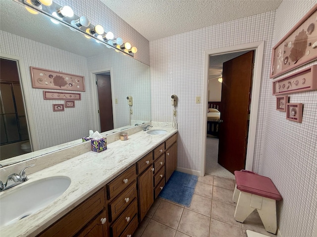 bathroom with tile patterned flooring, a textured ceiling, a sink, and double vanity