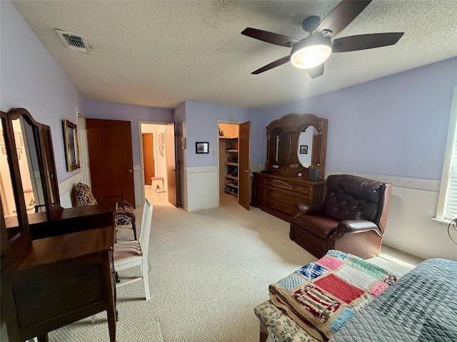 interior space with a walk in closet, visible vents, ceiling fan, and a textured ceiling