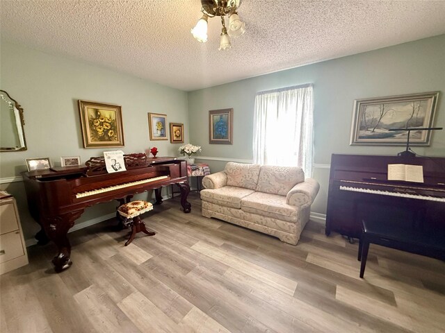 sitting room with wood finished floors, ceiling fan, and a textured ceiling
