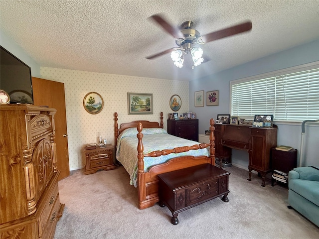 bedroom with light colored carpet, wallpapered walls, baseboards, a ceiling fan, and a textured ceiling