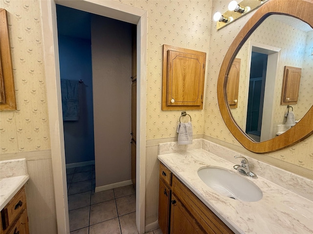 bathroom with tile patterned flooring, wallpapered walls, wainscoting, and vanity